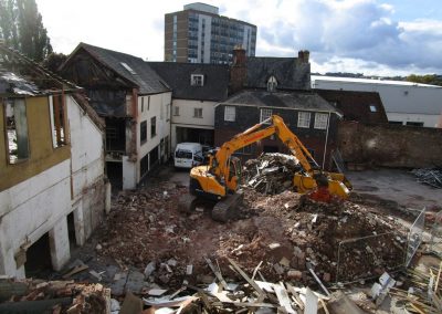 Large machinery working on rubble next to party wall